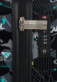 Valigia nera con doppie cerniere metalliche, una chiusura a combinazione e una superficie decorata con accenti geometrici verdi e bianchi.