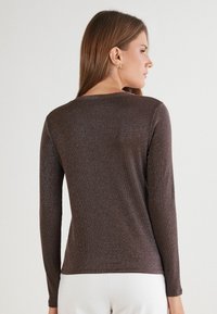 Braun metallic langärmliges Hemd mit rundem Ausschnitt und taillierter Silhouette. Weicher Textur mit subtiler Schimmer, ideal zum Schichten.