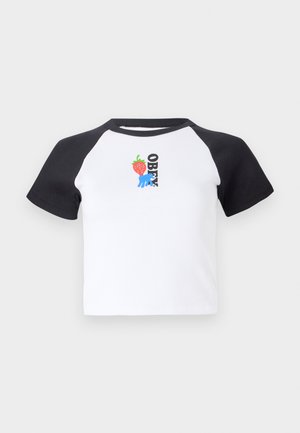 T-shirt de manga curta com corpo branco e mangas raglan pretas. Apresenta um gráfico de mãos azuis e um morango, além do texto "OBEY" em preto.