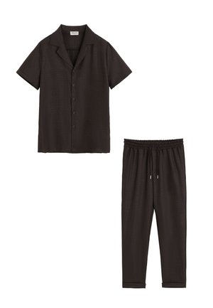 Chemise noire à manches courtes avec boutons et col, et pantalon assorti à taille élastiquée avec cordon et poignets, posé à plat sur fond blanc.