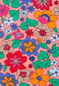 Tissu floral avec des fleurs vives en rouge, orange, violet et bleu, avec des feuilles vertes sur un fond pêche. Les motifs varient en taille.