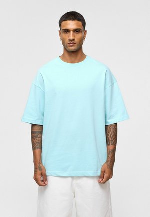 Lichtblauw oversized T-shirt van katoen, met een ronde halslijn en korte mouwen. Eenvoudig ontwerp zonder zichtbare patronen of versieringen.