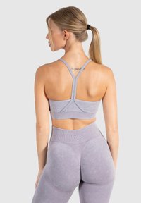 Lila naadloze sportbeha met verstelbare bandjes en een brede onderband, gecombineerd met bijpassende hoge taille leggings met een gladde textuur.