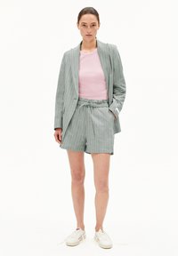 Helles graues, gestreiftes Blazer über einem rosa gerippten Top, kombiniert mit passenden Shorts und weißen Turnschuhen. Einfaches Design mit einem lässigen Schnitt.