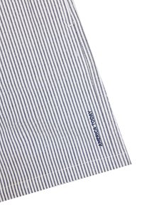 Striped shirt in white and navy, featuring vertical lines. Material appears smooth with a visible brand logo in navy on the bottom right.
