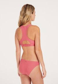 Ružový pruhovaný bikiny set s topom na pretekárskej chrbte a detailom s výrezom, spolu s ladiacimi dnom, vyrobený z hladkej, elastickej tkaniny.