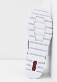 Semelle extérieure de sneaker grise avec une semelle en caoutchouc blanche texturée, présentant des rainures profondes pour la traction et un accent de marque rouge étiqueté "rieker".