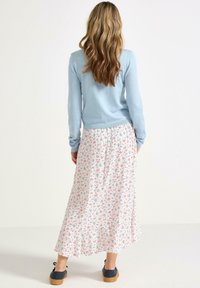 Lyseblå strikket sweater parret med en hvid blomster maxi-nederdel med små rosa og blå blomster samt sorte snørebåndssko med gummi sål.