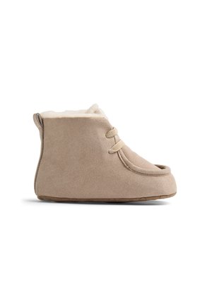Beige ruskinds hjemmesko i ankellængde med cremefarvet fleecefor, rundet tå, gummisål og to front-snørebånd, vist i profil på hvid baggrund.