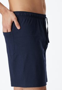 Dark blue swim shorts with an elastic waistband, adjustable drawstring, and a side pocket. Made from soft, lightweight fabric for comfort.