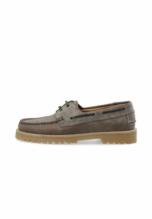 Bruine leren bootschoenen met een vetersluiting, contrasterende tan rubberen zool en gestructureerde stiksels langs de rand.