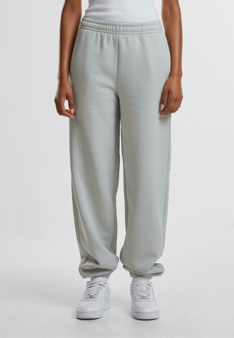 Lys grå joggebukser laget av mykt materiale, med elastisk midje og smale mansjetter, kombinert med hvite joggesko.