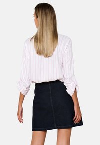 White shirt with pink stripes and rolled sleeves, paired with a dark denim mini skirt. Key features include contrasting colors and casual design.