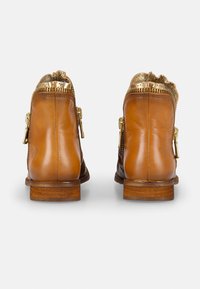 Tanfarbene Leder-Stiefeletten mit einem goldmusterierten Schaft, seitlichen Reißverschlüssen und einem gestapelten Holzabsatz.