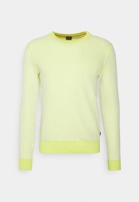 Pull en maille jaune clair avec col rond, manches longues, poignets côtelés et surface texturée avec un accent orange contrastant au niveau du col.