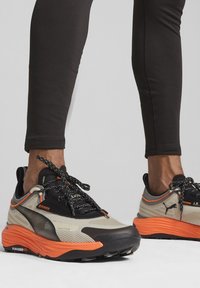 Scarpe sportive con tomaia in rete beige, dettagli neri e suola in gomma arancione. Lacci testurizzati e logo sul lato.