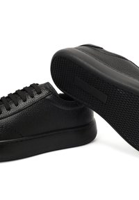 Czarne skórzane sneakersy z teksturowaną cholewką, okrągłym noskiem i sześcioma oczkami. Gumowa podeszwa z wzorem antypoślizgowym i gładkimi akcentami.