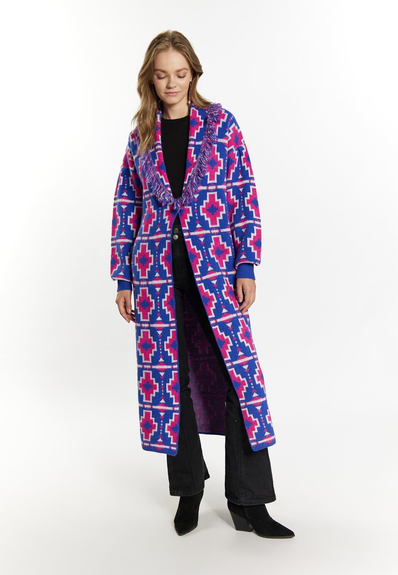 Cardigan lung cu fața deschisă, în nuanțe de albastru, roz și alb, cu un model geometric. Dispune de un guler franjurat și manșete ribbate, având o croială lejeră.
