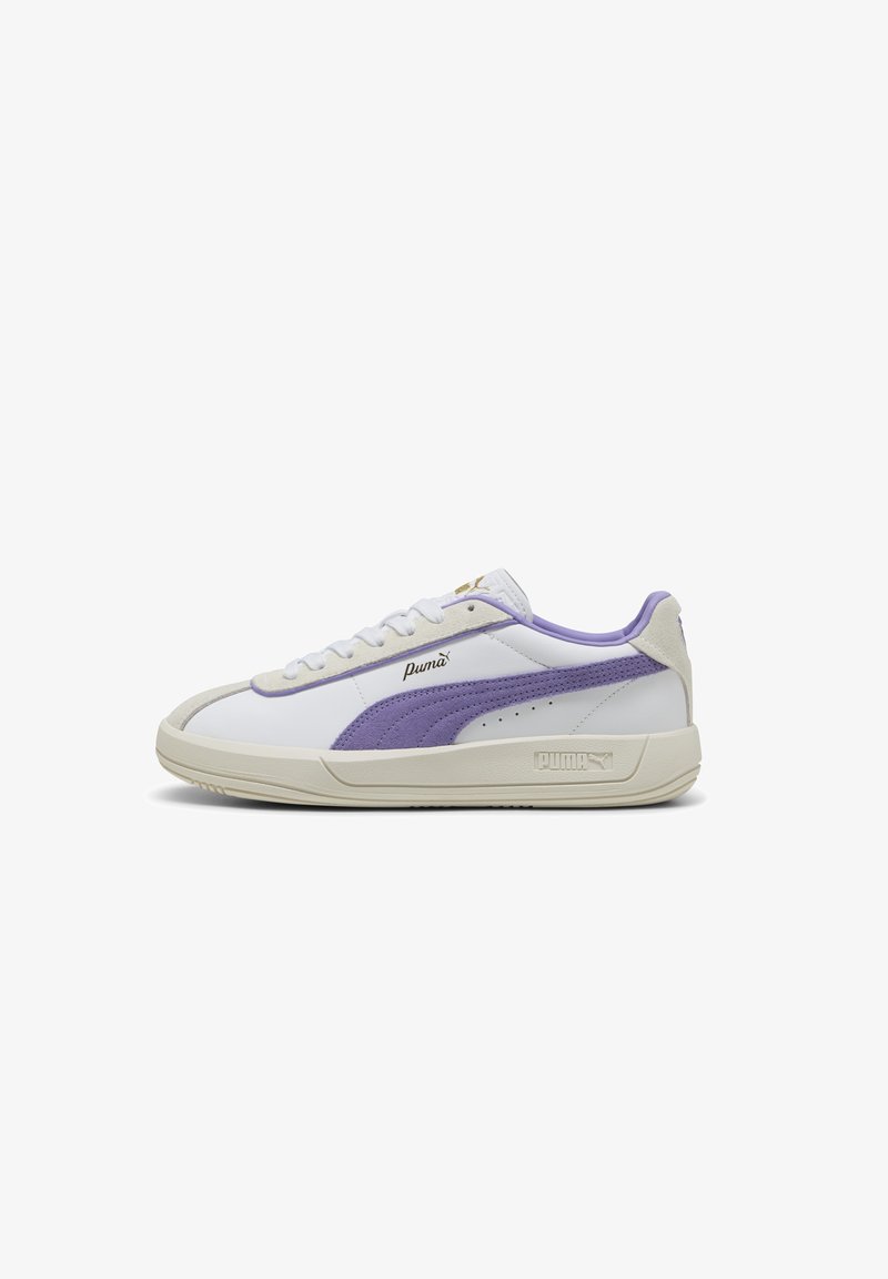Valged tossud violetsete nahkakunstdetailidega, kummist tald ja silmapaistev Puma logo. Lame paelte disain ja tekstuuriga detailid peal.