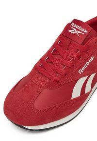 Punased sneakesid, millel on seemisnahast ja võrgust ülemine osa, ümar varvas, nööpidega disain ning valged aktsendid külgedel ja brändimärgistusel.