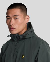 Veste imperméable vert foncé avec une fermeture éclair à l'avant, capuche ajustable et un logo jaune brodé sur la poitrine gauche. Texture lisse, sans motifs.
