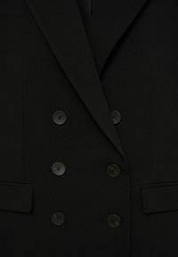 Černý dvouřadý blazer s šesti knoflíky a dvěma předními klopovými kapsami, se širokým klopovým límcem.