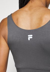 Dunkelgrauer Sport-BH mit glatter Textur, breiten Trägern und rundem Rücken. Verfügt über ein weißes Logo im oberen Rückenbereich.
