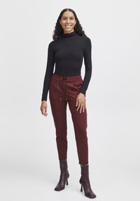 Black long-sleeve top paired with burgundy drawstring joggers and dark heeled ankle boots. The outfit features a fitted design and pockets.
