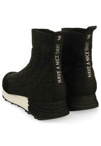 Bottines noires avec un dessus en tricot texturé, semelle en caoutchouc blanche et languettes en tissu affichant "BONNE JOURNÉE !" en imprimé argenté.