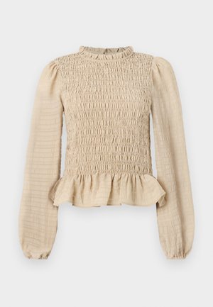 Krēms krāsas garām piedurknēm tops ar smockotu krūšu daļu, ruffles apakšmalu un peplum apakšmalu. Izgatavots no strukturētas auduma ar mīkstu apdari.