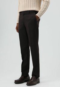 Donkerbruine op maat gemaakte broek, met een platte voorkant, slim fit, gemaakt van gladde stof, met zijzakken en een subtiele textuur. Gecombineerd met donkere schoenen.