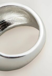 Sølvmetalring med en glat overflade og let struktureret inderside, der har en rund form og minimalistisk design.