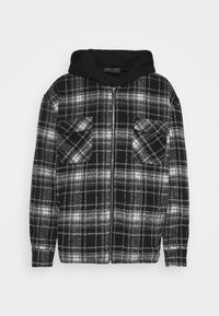 Black and white plaid jacket featuring a zip front, two chest pockets, and a black hood. Textured fabric with a soft finish.
