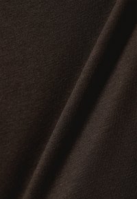 Σκούρο καφέ βαμβακερό ύφασμα με λεία, υφή επιφάνεια, που παρουσιάζει λεπτές ραβδώσεις και απαλά πτυχώσεις, τονίζοντας την ευέλικτη ποιότητά του.