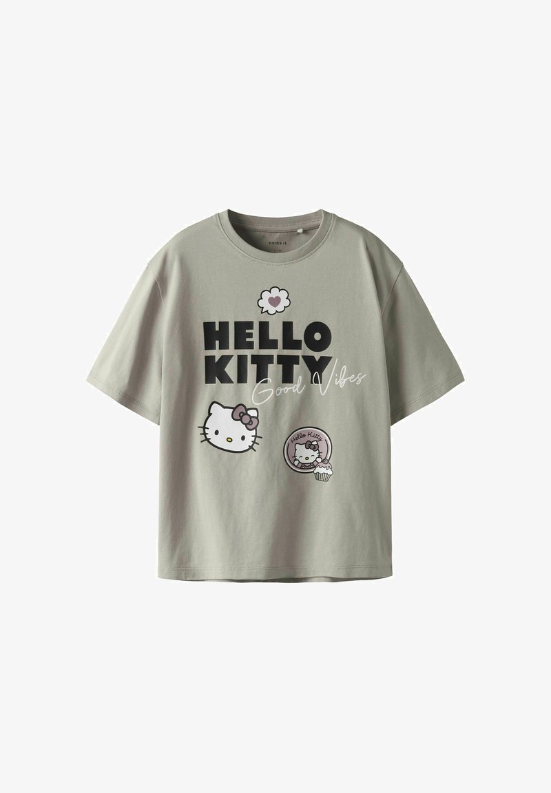 Lys grå t-shirt med korte ærmer, der har en "Hello Kitty" grafik, legende skrifttype og to karakterillustrationer med en cupcake.