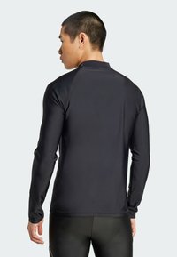 Zwarte lange mouwen sportshirt met hoge kraag en glad, rekbaar materiaal. Naadloos ontwerp met aangesloten manchetten voor comfort.
