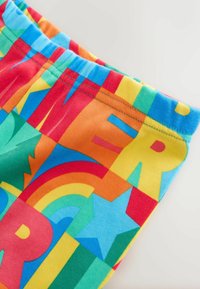 Värikkäät puuvillahousut, joissa on rohkeita kirjaimia ja muotoja punaisena, sinisenä, vihreänä, keltaisena ja oranssina, pehmeällä, joustavalla vyötärönauhalla.