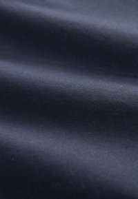 Glad donkerblauw stof met subtiele plooien en zachte lichtreflecties die de textuur benadrukken.