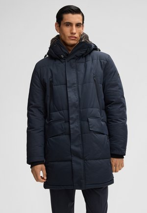 Donkerblauwe gewatteerde jas met een capuchon, voorzien van rits- en klepzakken, en een gestructureerde voering. De stof lijkt glad en waterafstotend.