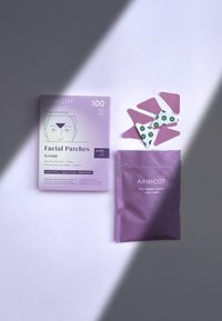 Emballage violet de patchs faciaux étiquetés "APRICO" et "Ectoin", présentant diverses formes de patchs dans des motifs roses et verts.