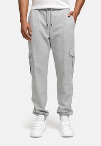 Gray cotton joggers with side cargo pockets, elastic waistband, and cuffs. Paired with white sneakers.