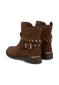 Braune Wildleder-Stiefeletten mit einem verstellbaren Riemen, der metallische Nieten aufweist, niedrigem Absatz und runder Zehenform. Reißverschluss auf der Rückseite.