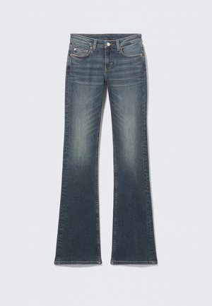 Jean en denim bleu évasé avec une finition délavée, cinq poches, surpiqûres contrastantes et une fermeture à bouton à la taille.