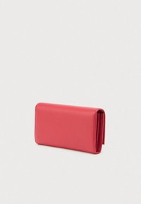 Rode textuur leren portemonnee, dubbelgevouwen en rechtopstaand op een lichte grijze achtergrond.