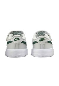 Ein Paar weiße und grüne Nike-Sneaker, von hinten gezeigt, mit grünen Nike-Logos und weißen Gummisohlen mit strukturierten Griffen.