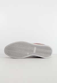 Shoe sole with a herringbone pattern, featuring a white rubber material. The design is flat with subtle branding and a rounded shape.
