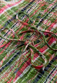 Tissu multicolore présentant un motif à carreaux dans des tons de vert, rose et blanc, avec des sections froncées et des liens pour la fixation.