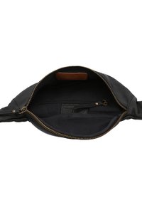 Interiér černé kožené tašky se zlatým zipem, tmavou látkovou podšívkou a malou zipovou kapsou. Uvnitř je viditelná hnědá kožená visačka.