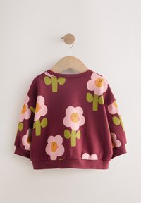 Sweat-shirt bordeaux pour enfants avec motif de fleurs roses souriantes et feuilles vertes, présenté sur un cintre en bois sur fond blanc.