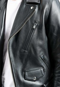 Schwarze Leder-Motorradjacke mit silbernen Reißverschlüssen, schrägem Frontreißverschlussfach und einer Druckknopfklappe. Glatte Textur und taillierte Passform.